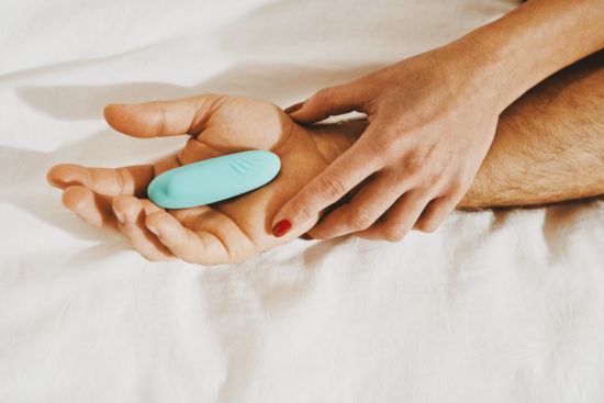 Woman and man holding vibrator on a bed