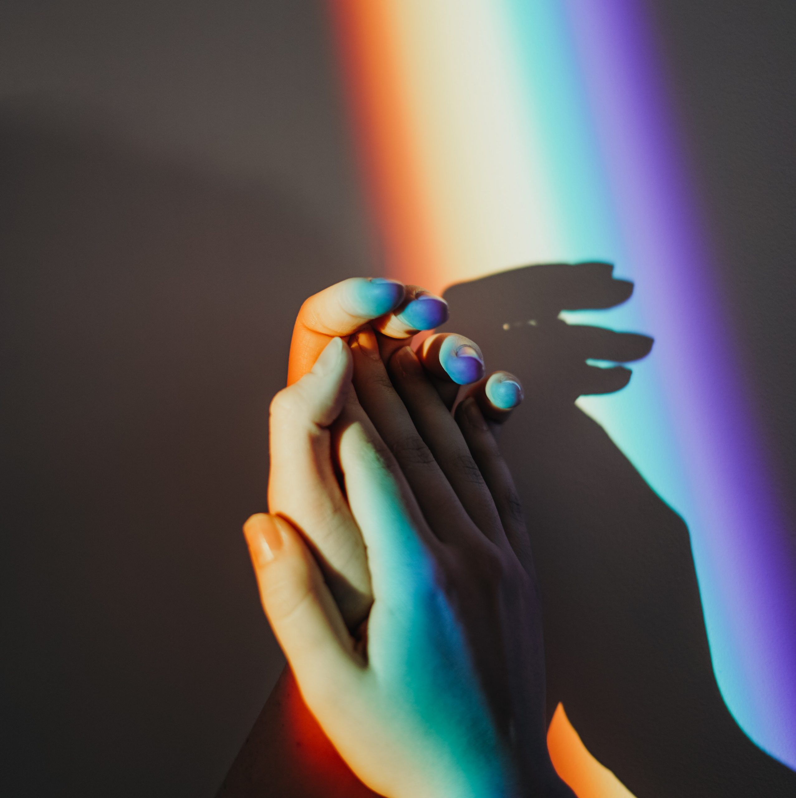 two hands touching with rainbow reflection