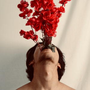 man choking on bouquet of red flowers