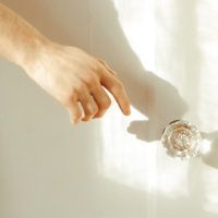 Hand reaching to grab a vintage crystal doorknob to open the door, promoting yes no maybe list.