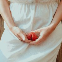 woman in white dress holding clit shaped fruit