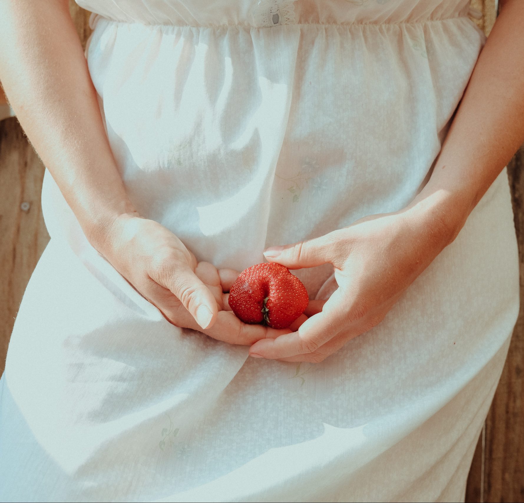 woman in white dress holding clit shaped fruit