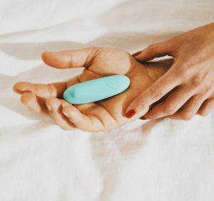 Woman and man holding vibrator on a bed
