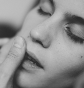 black and white close up of woman sensually touching her cheek