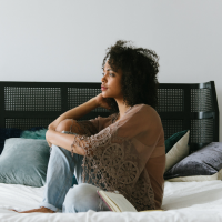 Girl sitting on a bed and looking into the distance