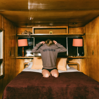 girl sitting on bed taking off sweatshirt