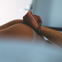 woman laying on bed with handcuffs