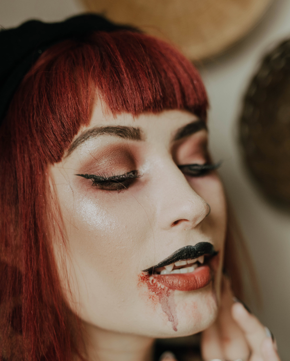 A young woman in her twenties, dressed up for halloween as a vampire