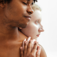 A pale woman embracing a man from behind