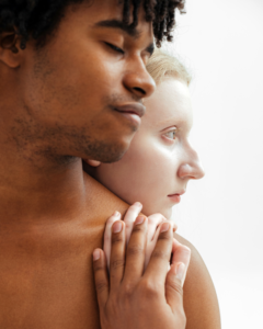 A pale woman embracing a man from behind