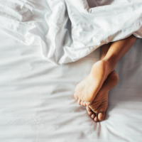 Woman's Feet on White Bedding