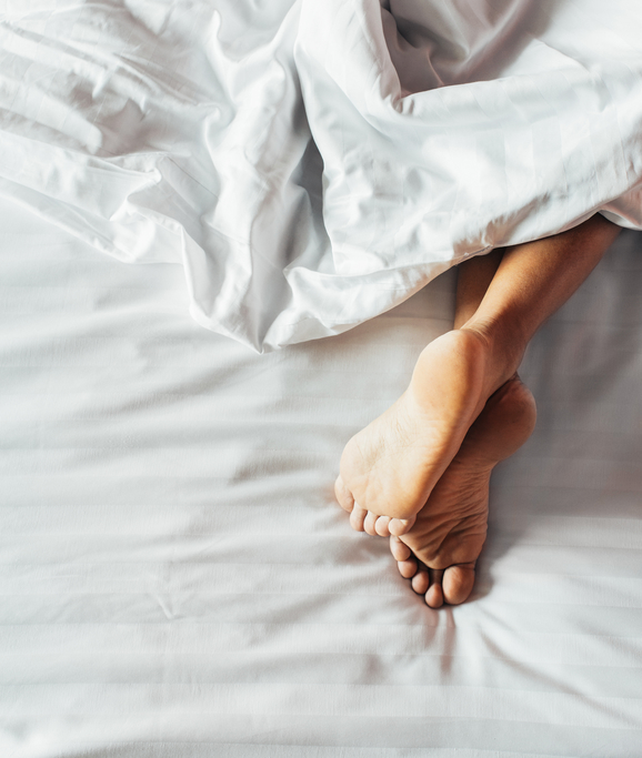 Woman's Feet on White Bedding