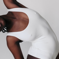 Woman in a white one piece, stretching arm over her head