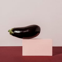 An eggplant on a pink block.