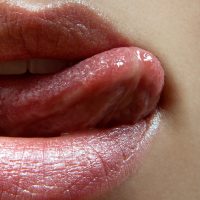 closeup shot of mouth with tongue licking top lip