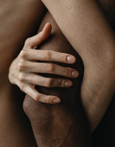 White woman's hand wrapped around black man's elbow.
