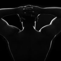 Silhouette of a strong shirtless man outlined in rim lighting.