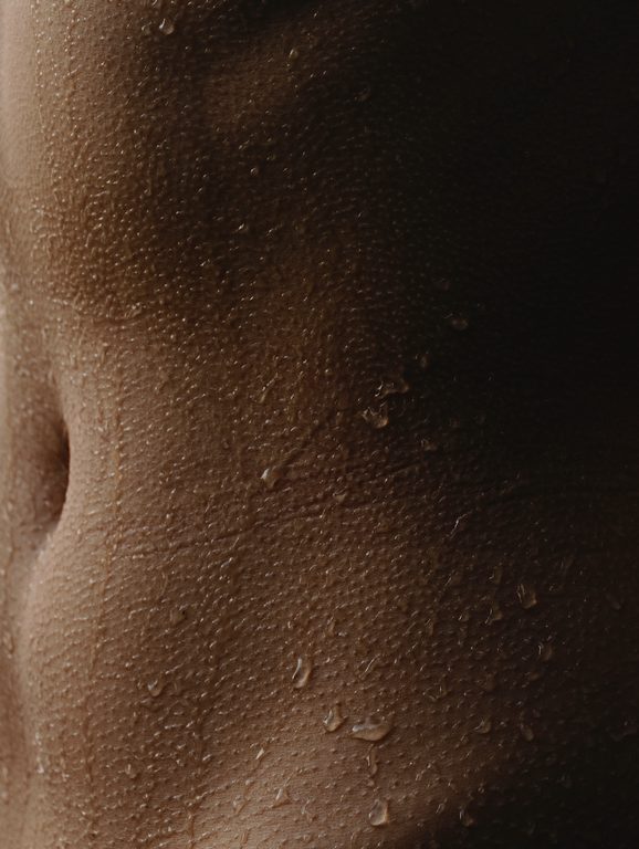 Vertical photo of close up skin woman with skin texture with water droplets.