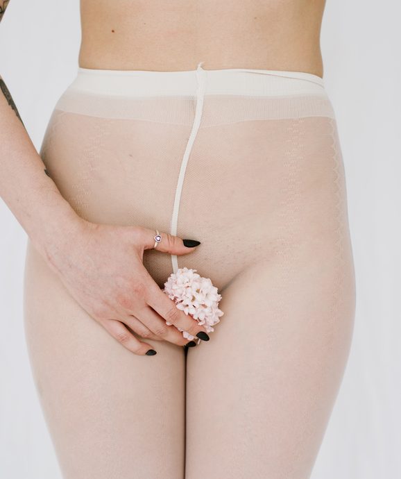 Closeup of woman's body in white tights with flower vagina