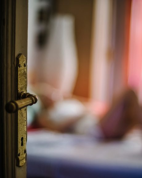 Woman lying on the bed seen through the door.