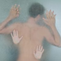 Blurred silhouette of a young naked man in a shower room with two women behind wet frosted glass