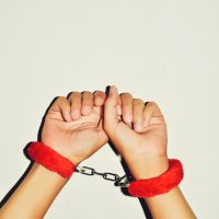 man wearing red sexy fluffy handcuffs in her wrists