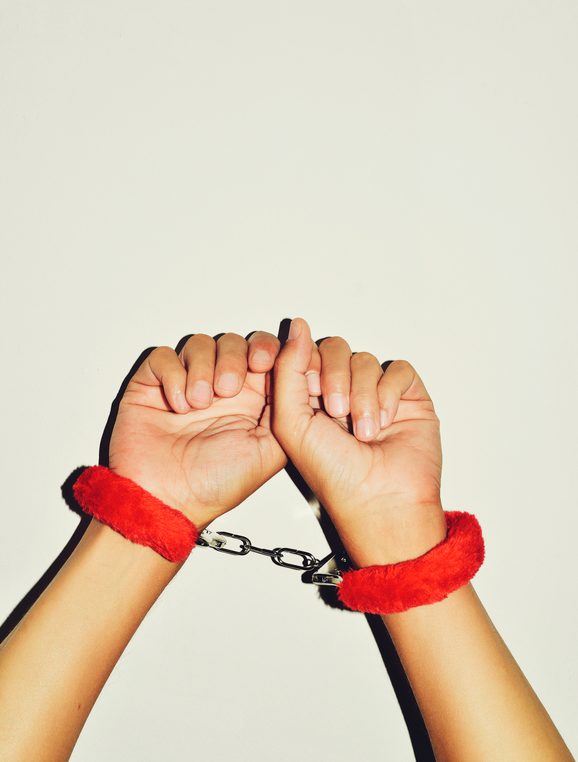 man wearing red sexy fluffy handcuffs in her wrists