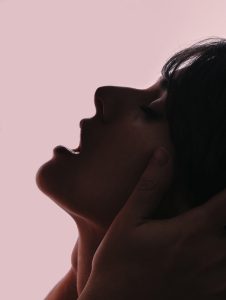 Woman leaning back making a open mouth face from orgasm
