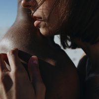 Close up Portrait of woman hugs an African man. .Love story of a couple in the desert in summer. The blue sky above them. Portrait of the face in profile close up female face. Natural girl without makeup. Multiethnic Love Couple.