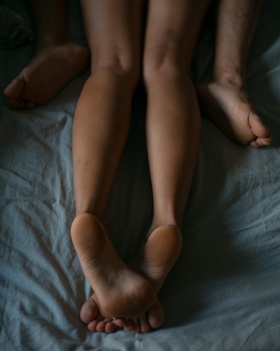 crossed legs of a girl and legs of a man on the bed
