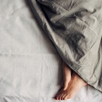 Feet of a woman sleeping under a comforter.