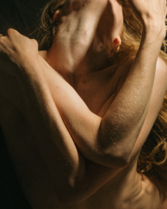 Artistic photo of a woman embracing herself, representing sexual pleasure and exploring blended orgasms